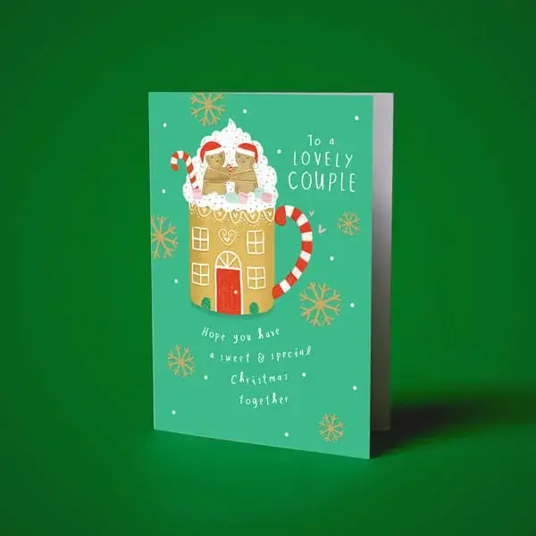 Christmas greeting card for a lovely couple featuring a festive mug-shaped gingerbread house with candy cane handles and snowflake decorations.
